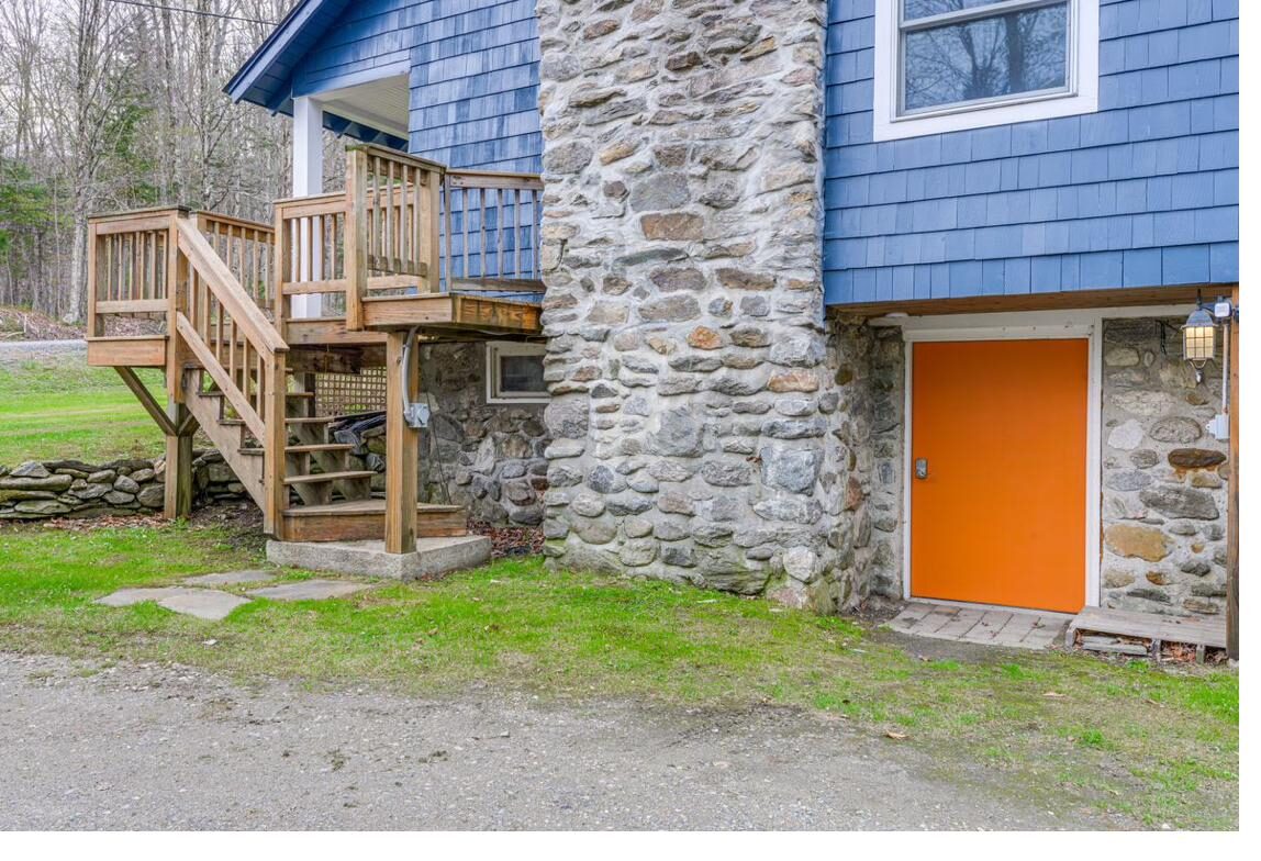 Orange door beside the stone chimney