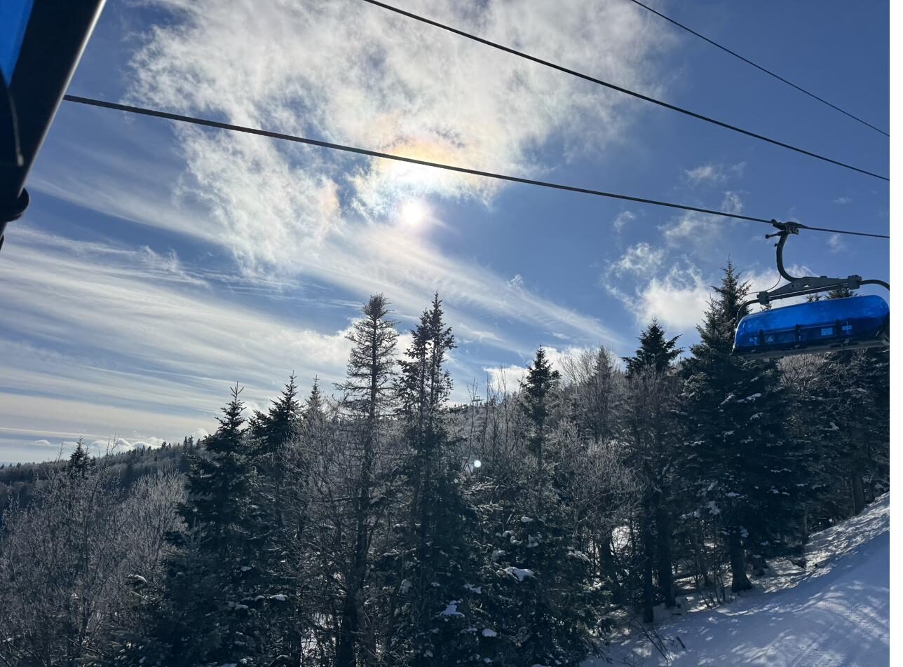 Riding the Bluebird Express chairlift above snowy evergreens at Mount Snow