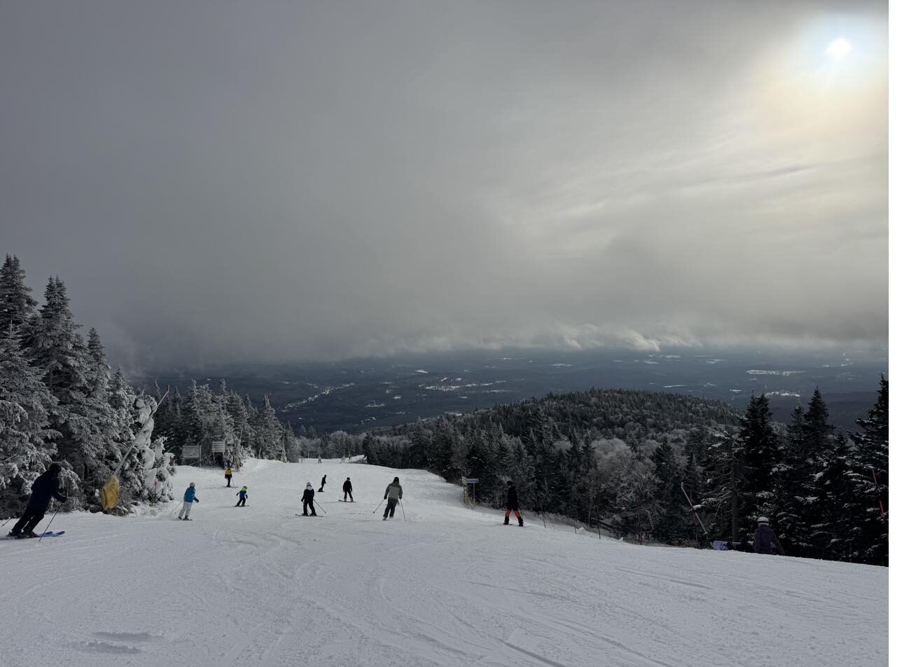 Skiers heading down a trail with mountain views